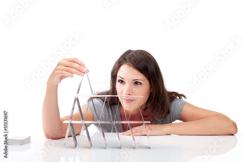Photo: Beautiful young woman is building a house of cards Beautiful young woman is building a house of cards