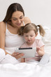 Child using tablet with her mother