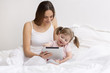 Child using tablet with her mother