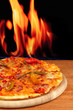 Photo: Tasty pepperoni pizza on wooden board on flame background Tasty pepperoni pizza on wooden board on flame background