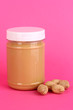 Delicious peanut butter in jar of peanut near on pink