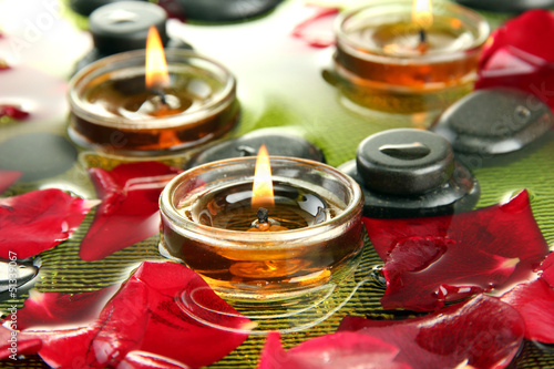 Photo: spa stones with rose petals and candles in water on plate spa stones with rose petals and candles in water on plate
