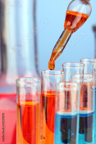 Photo: Laboratory pipette with drop of color liquid over glass test Laboratory pipette with drop of color liquid over glass test