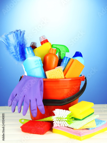 Photo: Cleaning items in bucket on color background Cleaning items in bucket on color background