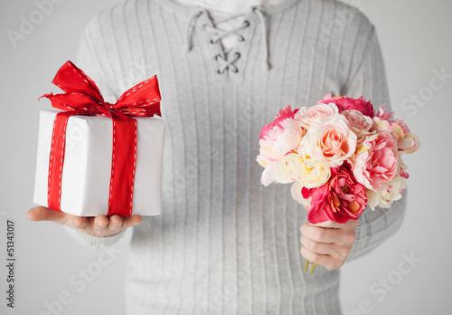 Photo: man holding bouquet of flowers and gift box man holding bouquet of flowers and gift box