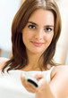 Smiling woman watching TV at home