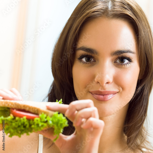 Photo: Happy smiling woman with sandwich at home Happy smiling woman with sandwich at home