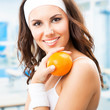 Woman with orange, at fitness center