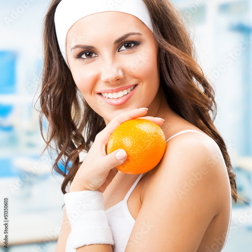 Photo: Woman with orange, at fitness center Woman with orange, at fitness center