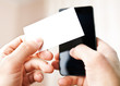 Man holding blank business card and dialing numbers on mobile ph