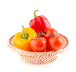 tomatoes and peppers in a wicker basket on a white background