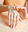 Young woman applies cream on her hands after bath. Focus on hand