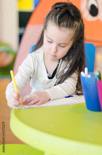 Photo: Little girl is drawing with pen in preschool Little girl is drawing with pen in preschool