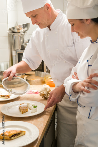 Photo: Male baker showing apprentice serving puff pastry Male baker showing apprentice serving puff pastry