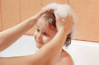 Mom's hands are washed the little blond boy's head in bathroom