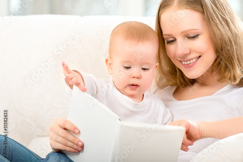 Photo: Mother reading a book a little baby on the sofa Mother reading a book a little baby on the sofa