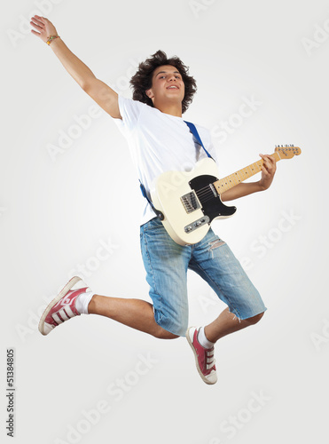 Photo: young man playing on electro guitar and jumping young man playing on electro guitar and jumping