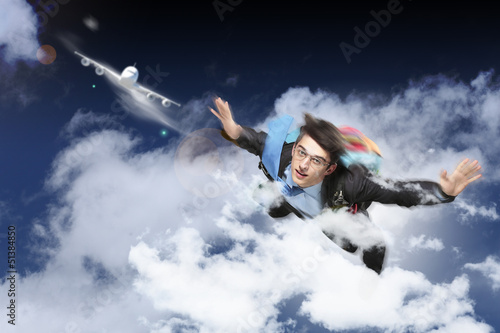 Photo: Young businessman flying with parachute on back Young businessman flying with parachute on back