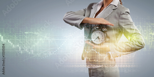 Photo: Business woman holding alarmclock Business woman holding alarmclock