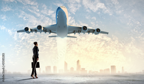 Photo: Business woman looking at airplane in sky Business woman looking at airplane in sky
