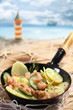 Fischpfanne vor Strand mit Leuchtturm