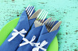 Forks and knives wrapped in blue paper napkins,
