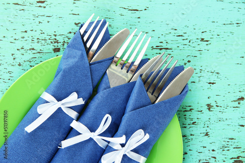 Photo: Forks and knives wrapped in blue paper napkins, Forks and knives wrapped in blue paper napkins,