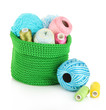 Colorful yarn for knitting in green basket isolated on white