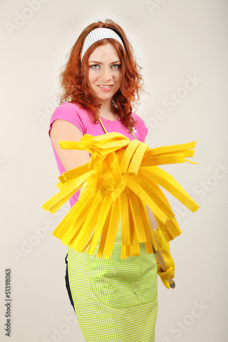 Photo: Young housewife with mop on grey background Young housewife with mop on grey background