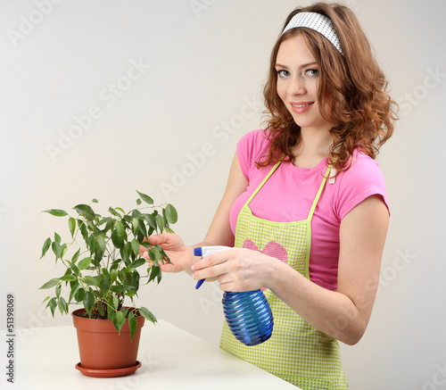 Photo: Young woman cultivating flowers on grey background Young woman cultivating flowers on grey background
