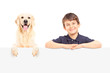 A smiling boy and Labrador retriever posing behind a panel