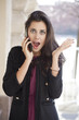Foto: Young happy woman calling by phone on the street Young happy woman calling by phone on the street