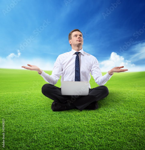 Photo: business man with notebook sitting on grass business man with notebook sitting on grass