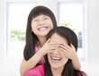 Photo: happy little girl cover her mother eyes for fun happy little girl cover her mother eyes for fun