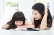 Photo: young mother and her daughter lie on the floor and reading a bo young mother and her daughter lie on the floor and reading a bo