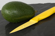 Avocado mit Messer auf Schieferplatte