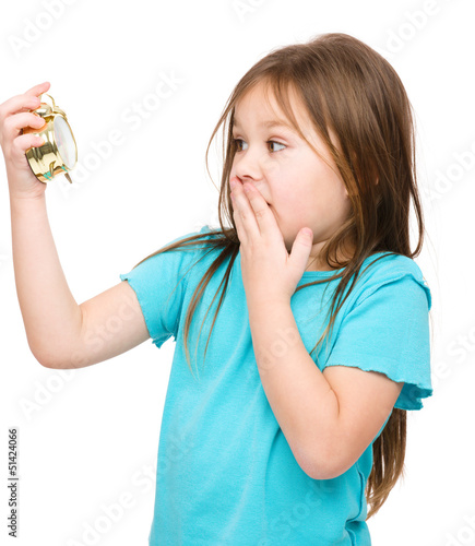 Photo: Little girl is looking at alarm clock Little girl is looking at alarm clock