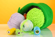 Colorful yarn for knitting in green basket on orange background