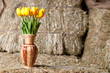 Yellow tulips in a wicker vase on background of hay.