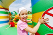 Joyful little girl has fun at inflatable attractions in park