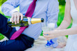 groom pours champagne glasses in hand bride