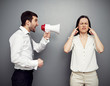man screaming in megaphone at the woman