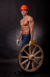 Muscular young man with a wagon wheel on a black background.