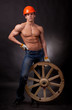 Muscular young man with a wagon wheel on a black background.