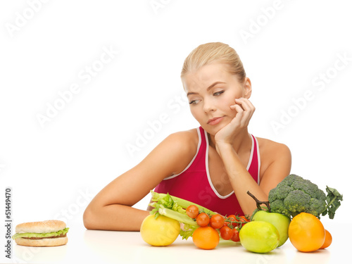 Photo: doubting woman with fruits and hamburger doubting woman with fruits and hamburger