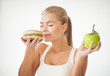 woman smelling hamburger and holding apple