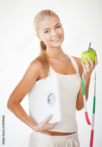 Photo: sporty woman with scale, apple and measuring tape sporty woman with scale, apple and measuring tape