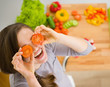 Smiling young woman holding cherry tomatos in front of face