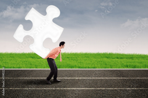 Photo: Asian man carry puzzle on the road Asian man carry puzzle on the road