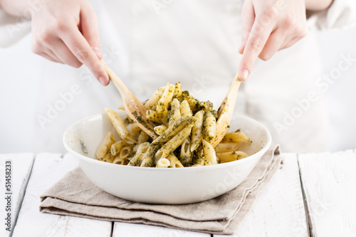 Photo: Cook mixing pesto with penne rigate pasta Cook mixing pesto with penne rigate pasta